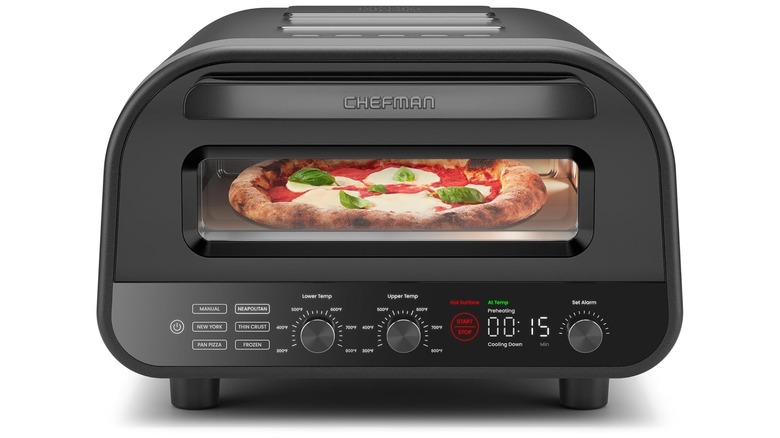 A black CHEFMAN Indoor Pizza Oven with a spinach and mozzarella pizza inside