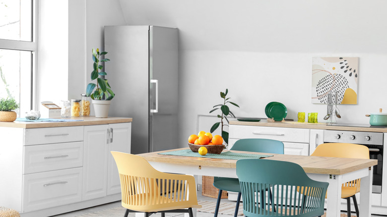 A bright and airy white kitchen, with a bowl of oranges on a dining table
