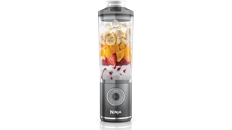 A Ninja Blast Max filled with cream, sliced strawberries, mango pieces, banana slices, and ice