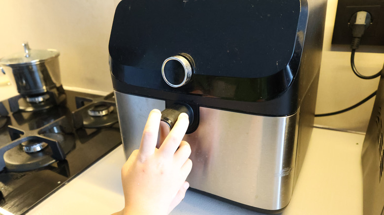 A person using an air fryer on a kitchen counter