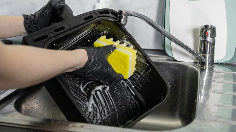 A person cleaning an air fryer basket