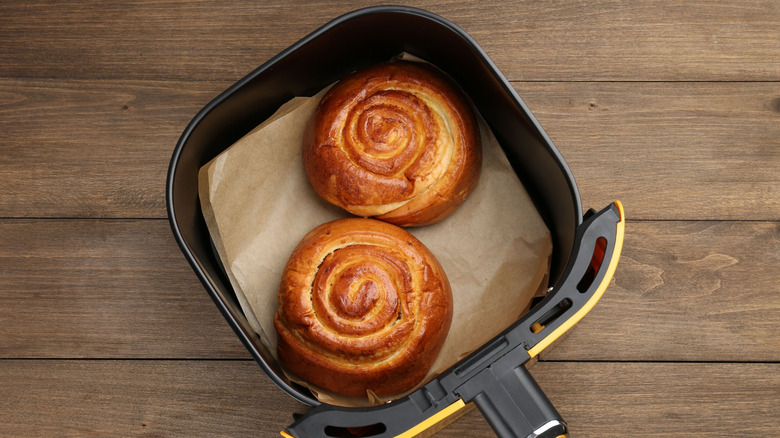 An air fryer basket with two cinnamon rolls