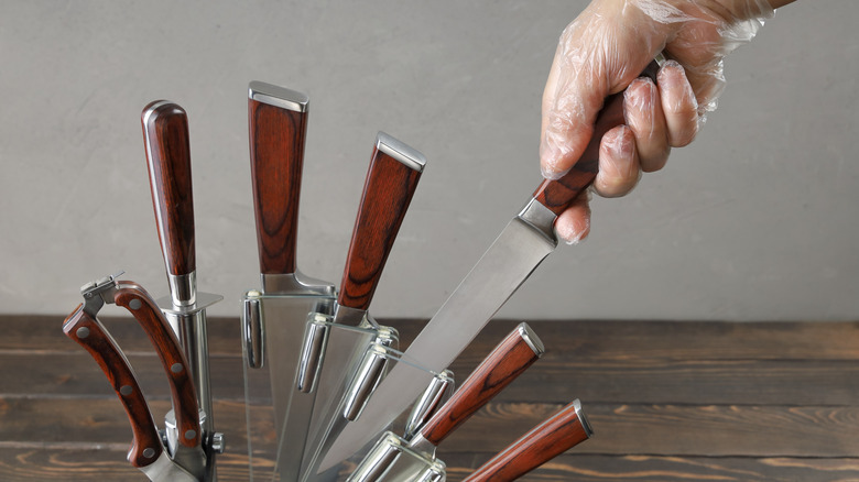 A hand taking a knife out of a block set