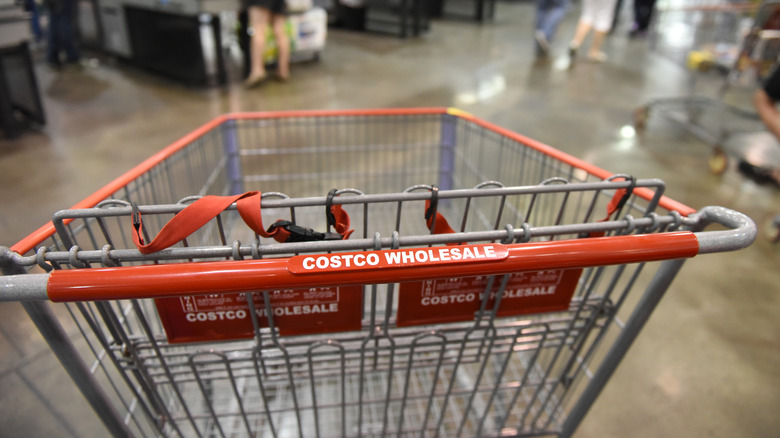 Costco shopping cart in warehouse with shoppers.