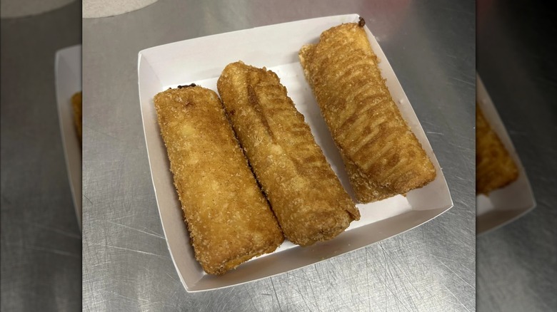 Three Arby's Peach Cobbler rolls in a white paper tray