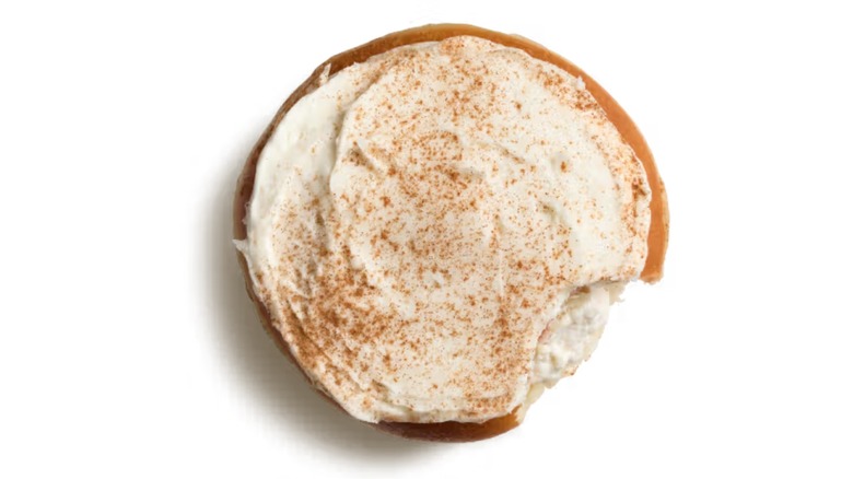 A Krispy Kreme unglazed donut filled with a white cream, topped with white frosting and brown crumbles/seasoning