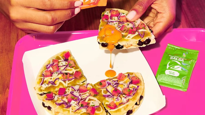 A Cantina Chicken Mexican Pizza with orange-colored citrus salsa, being pulled apart over a hot pink tray