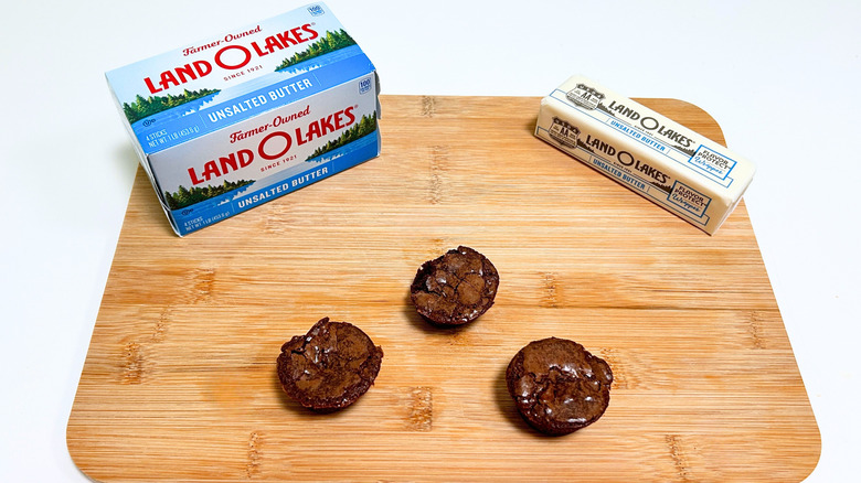 A box of Land O'Lakes Unsalted Butter next to a stick of butter and three brownie bites
