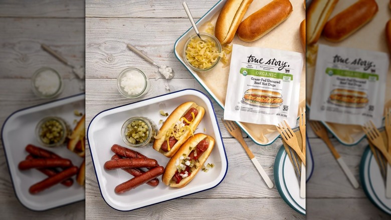 True Story Organic Grass-Fed Beef Hot Dogs on a table, next to buns and toppings