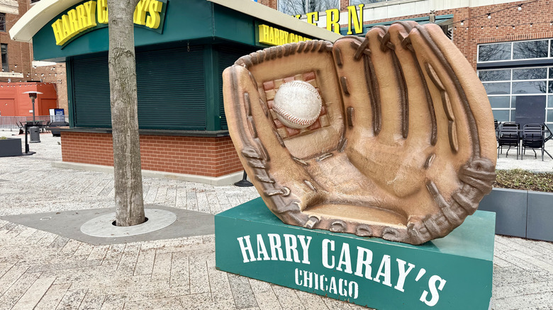 A sign for Harry Caray's with a large baseball glove statue