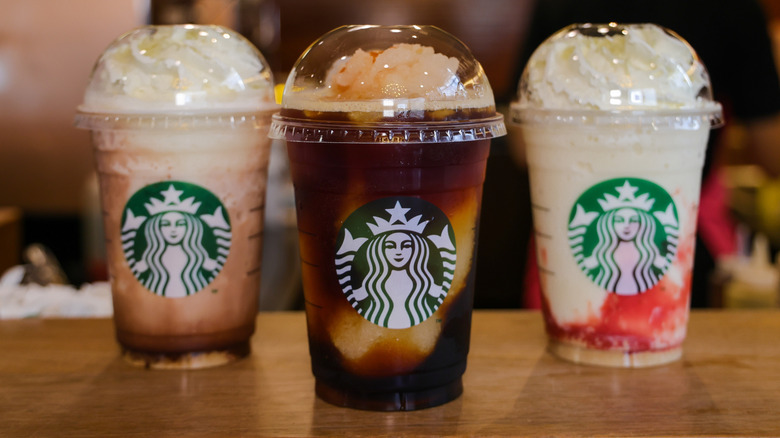 An assortment of three Frappuccinos on a table inside Starbucks