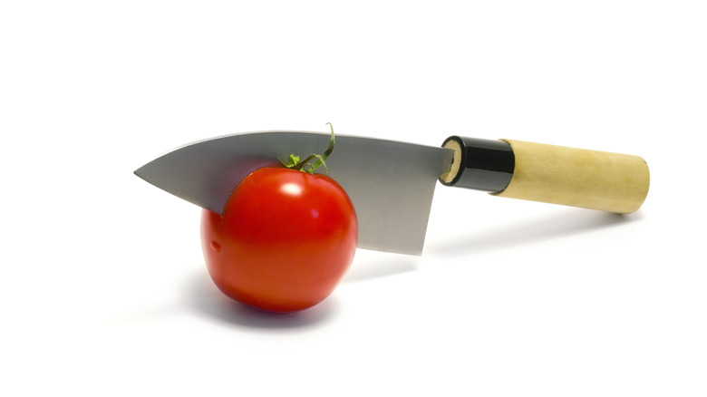Deba knife cutting into tomato