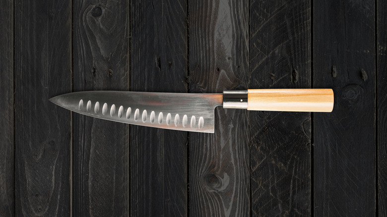 Gyuto knife with light wood handle on dark wood surface