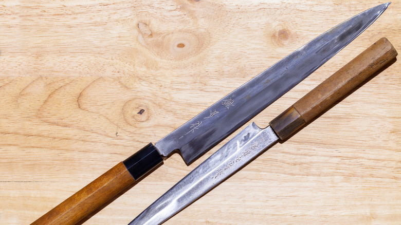 Two long yanagiba knives on wood surface