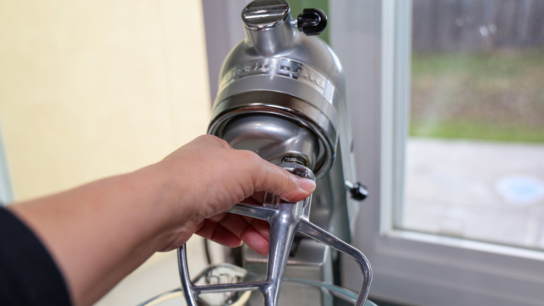 A hand attaching a beater to a KitchenAid mixer
