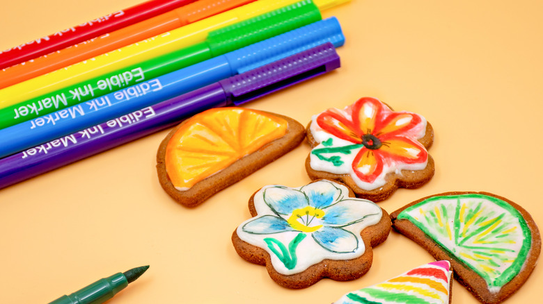 Edible ink markers next to sugar cookies with drawn-on decorations