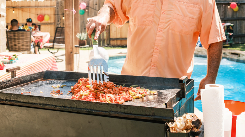 Man cooking meat and vegetables on a griddle
