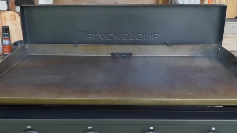 A Blackstone griddle smoking while seasoning