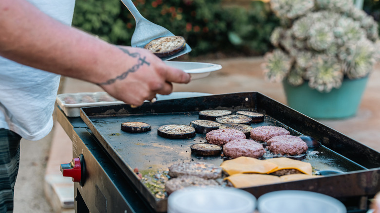 Man getting food from a hot griddle