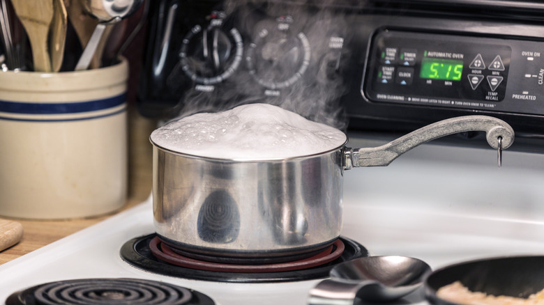 Pot cooking on electric stove with water boiling over