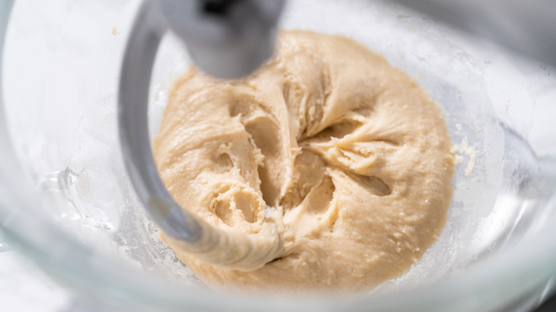 Dough hook kneading pizza dough in a bowl