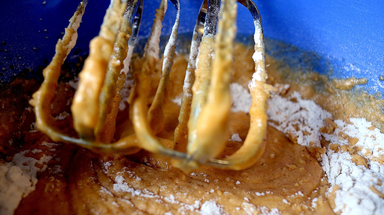 Hand mixer beaters mix batter with flour left along the sides