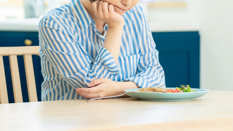 Disappointed woman with a plate of vegetables