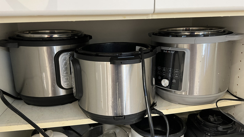 3 Instant Pot pressure cookers on a shelf in a pantry
