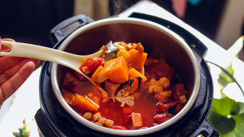 A stew of chicken, sweet potatoes, and tomatoes inside an Instant Pot with some spooned out