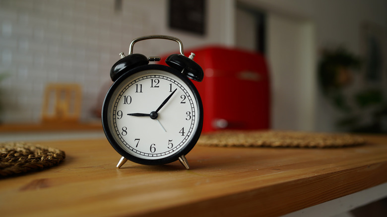A vintage black alarm clock on a wooden kitchen counter
