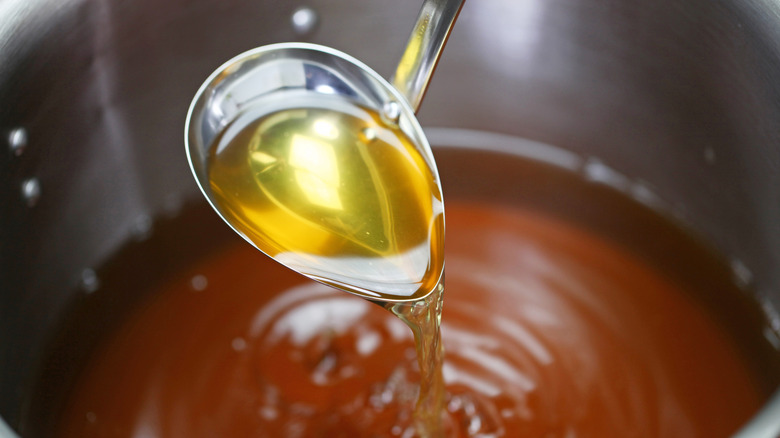 A ladle pouring stock into a pot