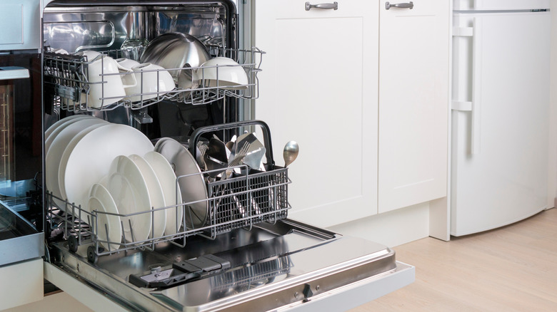 An open dishwasher filled with plates, bowls, and utensils