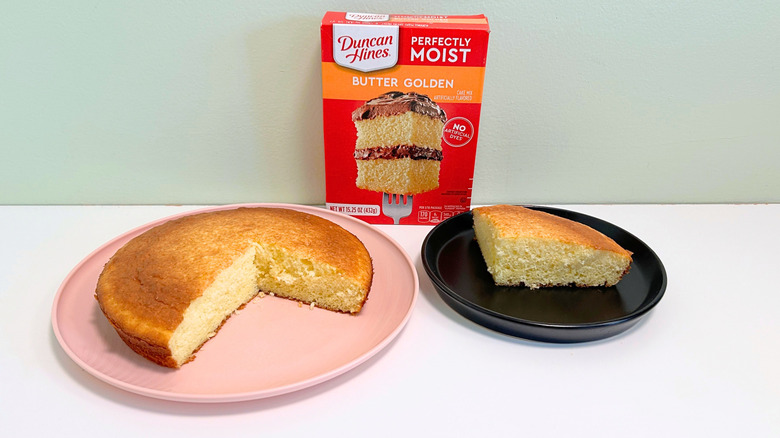 A box of Duncan Hines Perfectly Moist Butter Golden Cake Mix next to two plates of cake