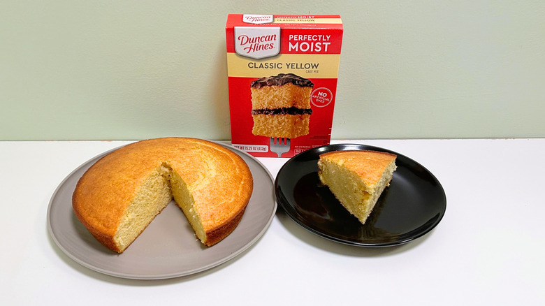A box of Duncan Hines Perfectly Moist Classic Yellow Cake Mix next to two plates of cake