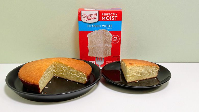 A box of Duncan Hines Perfectly Moist White Cake Mix next to two plates of cake