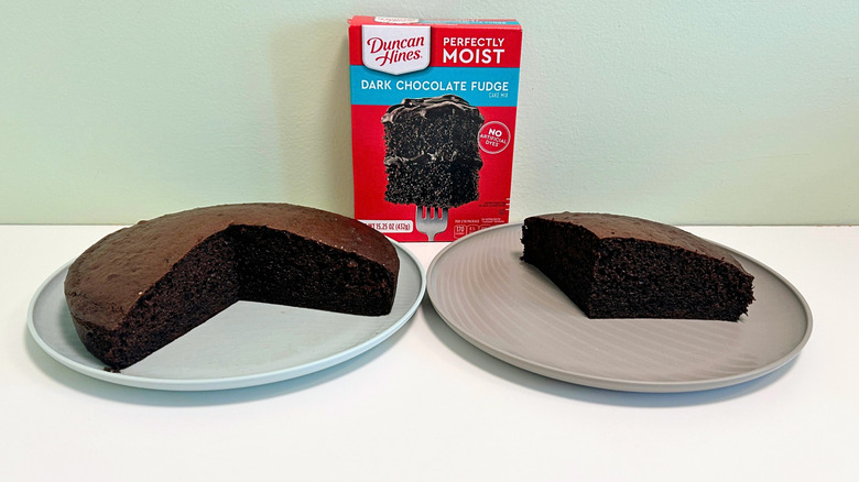 A box of Duncan Hines Perfectly Moist Dark Chocolate Fudge Cake Mix next to two plates of cake
