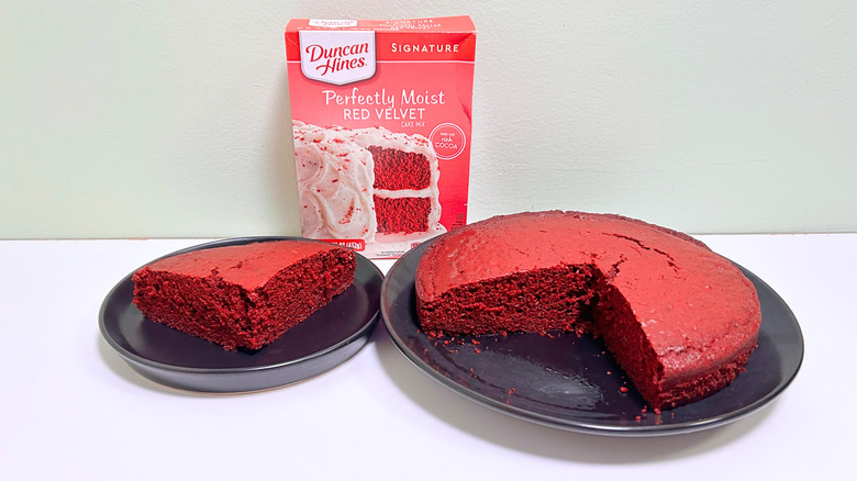 A box of Duncan Hines Perfectly Moist Red Velvet Cake Mix next to two plates of cake
