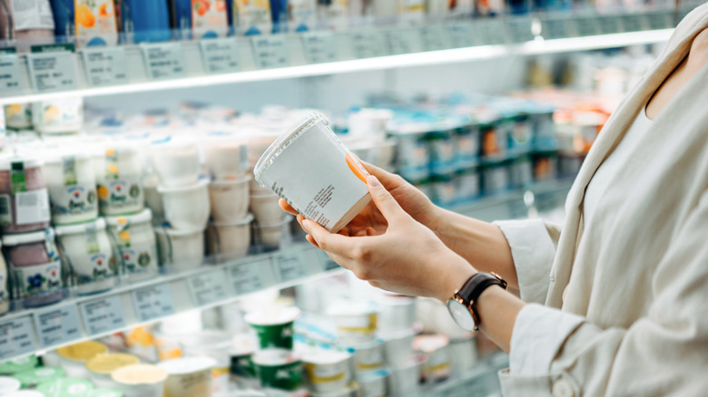 person holding item in dairy aisle of grocery store
