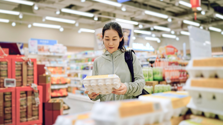 woman looks at eggs in grocery store