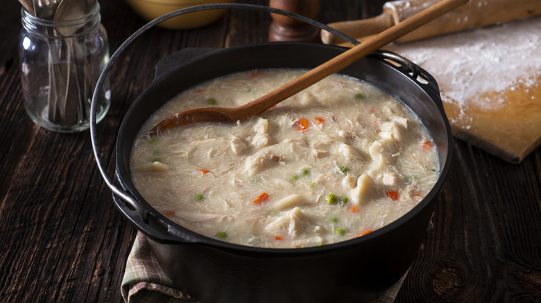 Cast iron pot of chicken soup with wooden spoon