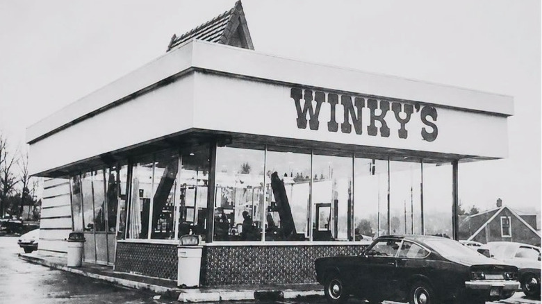 Black and white photo of Winky's storefront with a car parked out front
