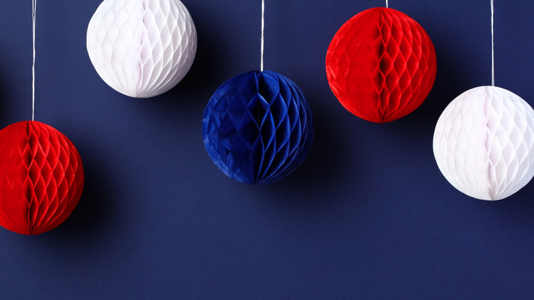Red, white, and blue paper ball decorations hanging against navy blue wall