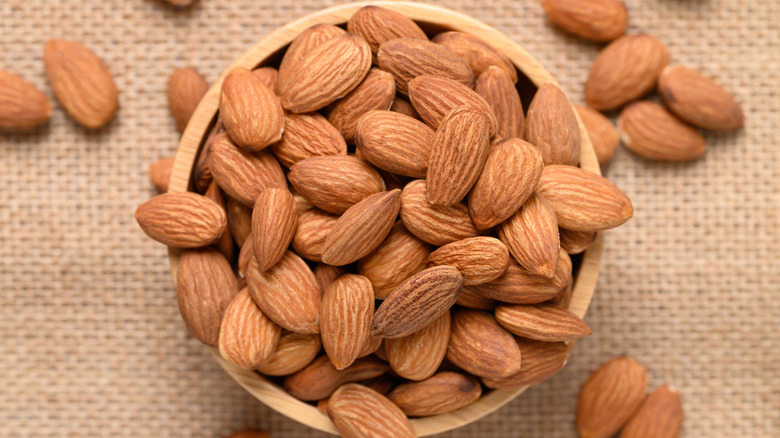 Close-up of a wooden bowl full of raw, whole almonds