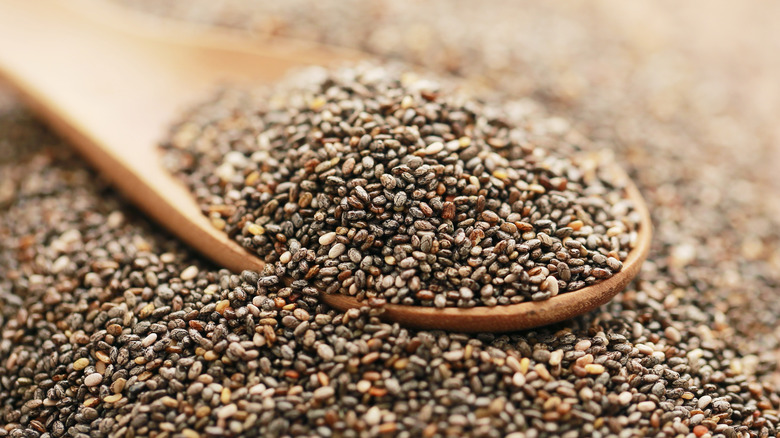 Overflowing wooden spoon of chia seeds on a rustic table