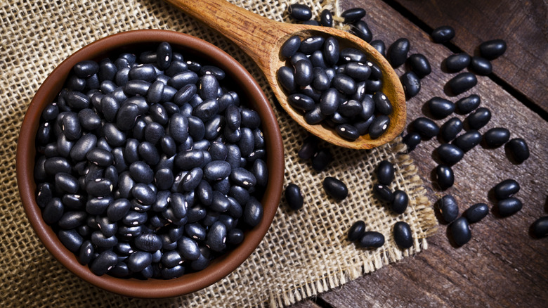 Wooden bowl and spoon full of uncooked black beans