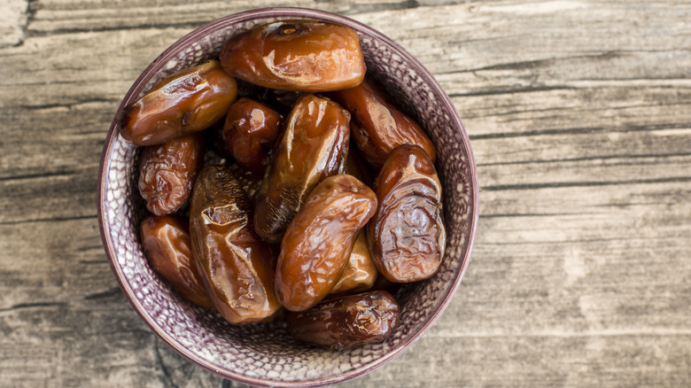 A bowl of dates on a rustic wooden table.