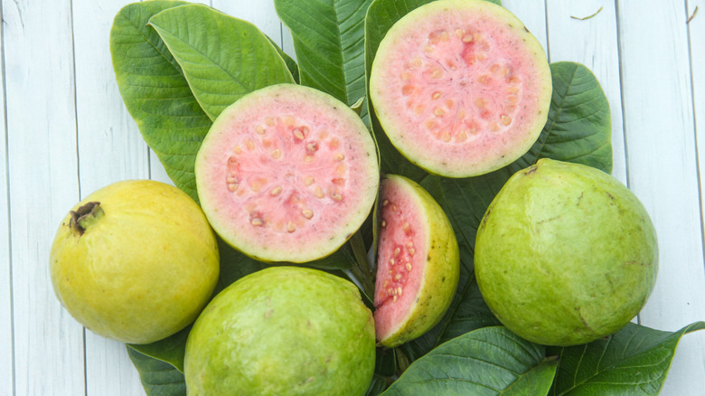 cut open ride guava fruit surrounded by whole guava