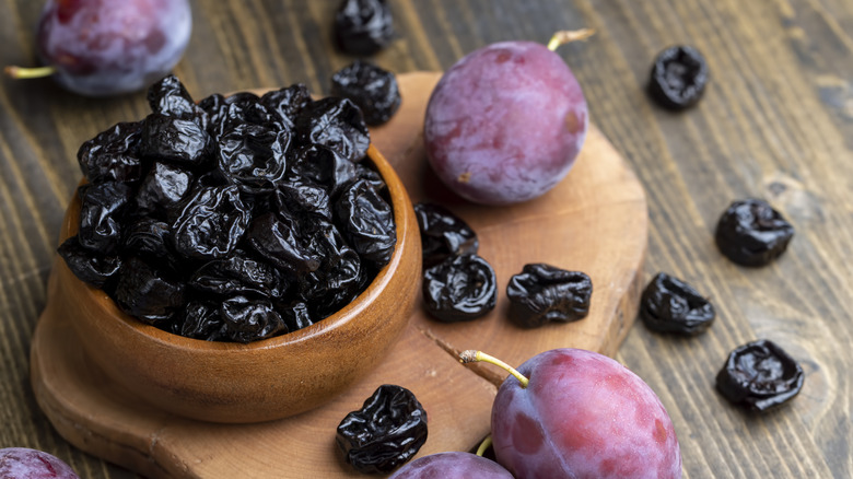 Black pile of prunes along with ripe plums.