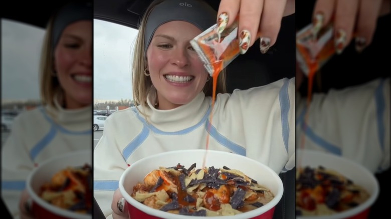 Woman squeezes hot sauce on bowl of soup