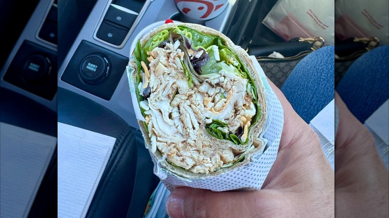 Hand holding halved chick fil a cool wrap in car